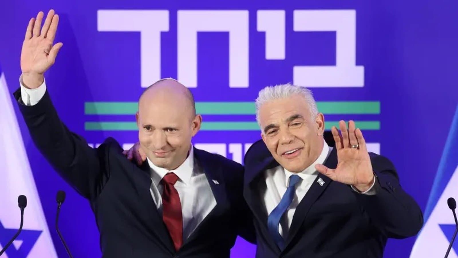 Naftali Bennett and Yair Lapid waving together on stage at a joint press conference in Herzliya.