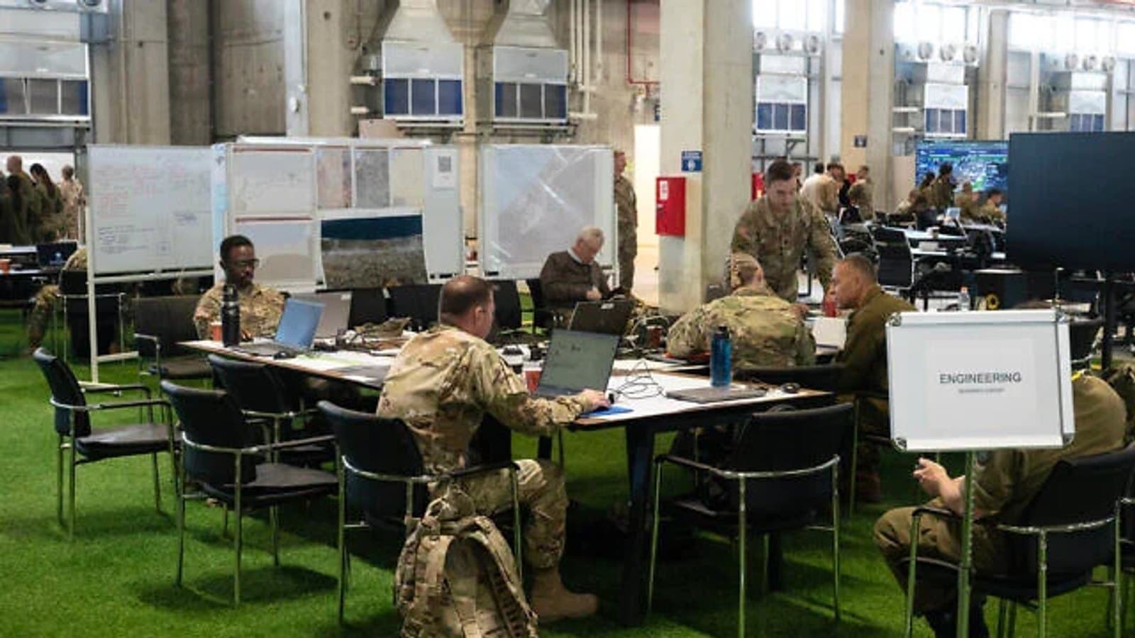 Military personnel working at desks and briefing boards inside the Civil Military Coordination Center.