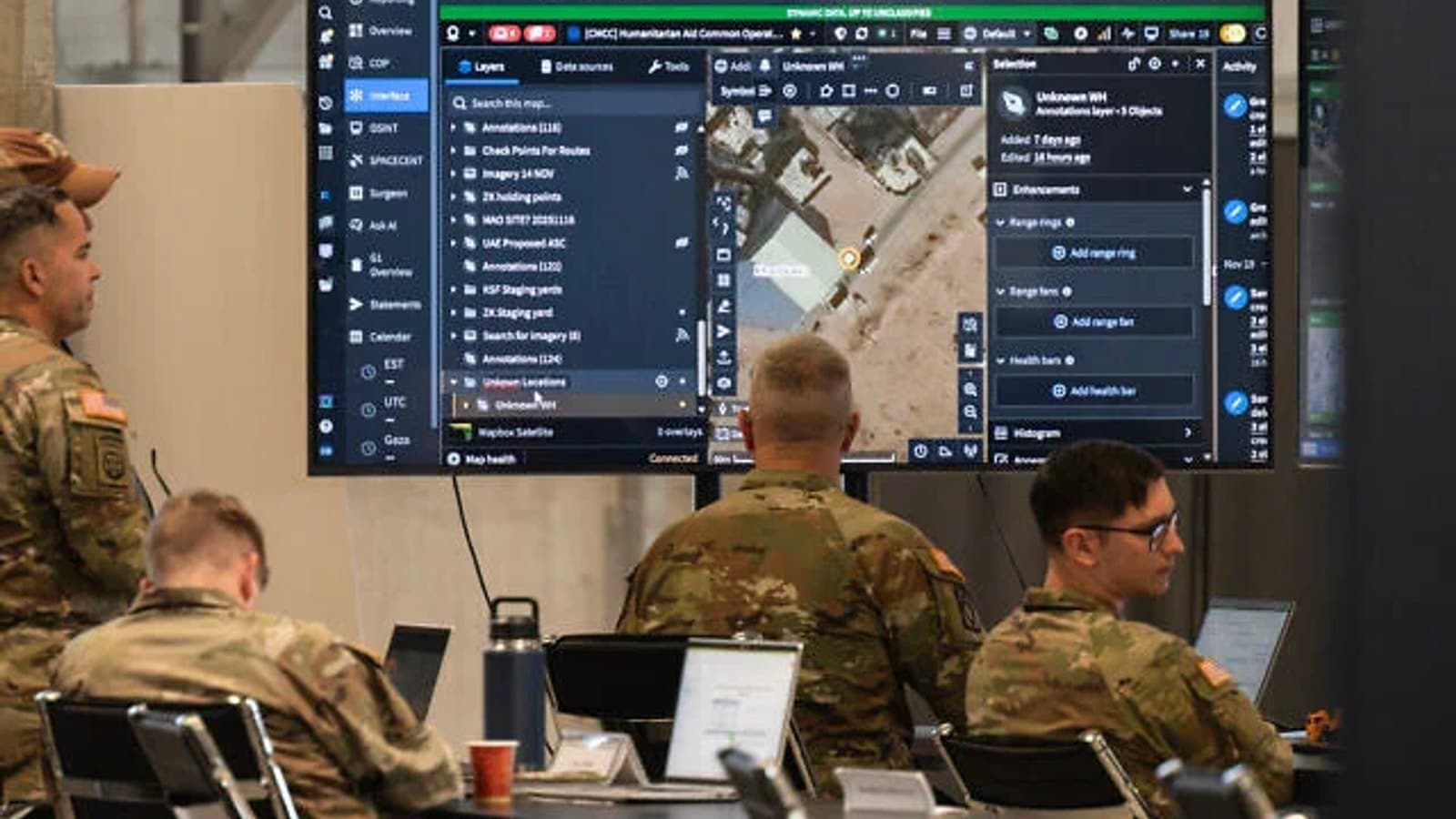 Soldiers viewing a mapping and intelligence workspace on large screens inside the Civil Military Coordination Center.
