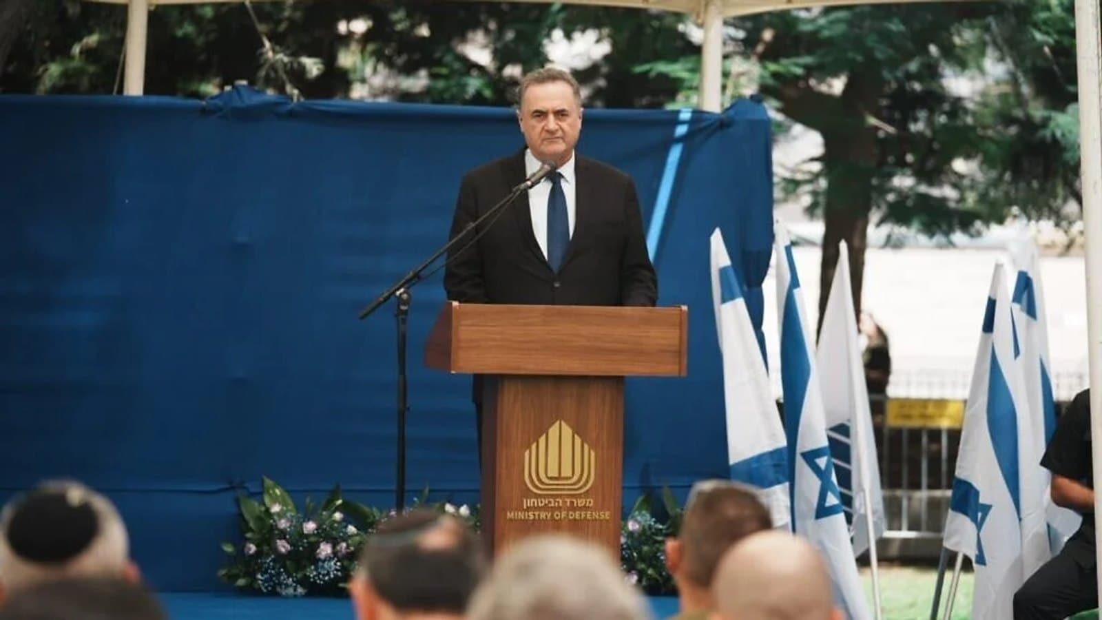 Defense Minister Israel Katz speaking at a podium at the Ministry of Defense, flanked by Israeli flags.