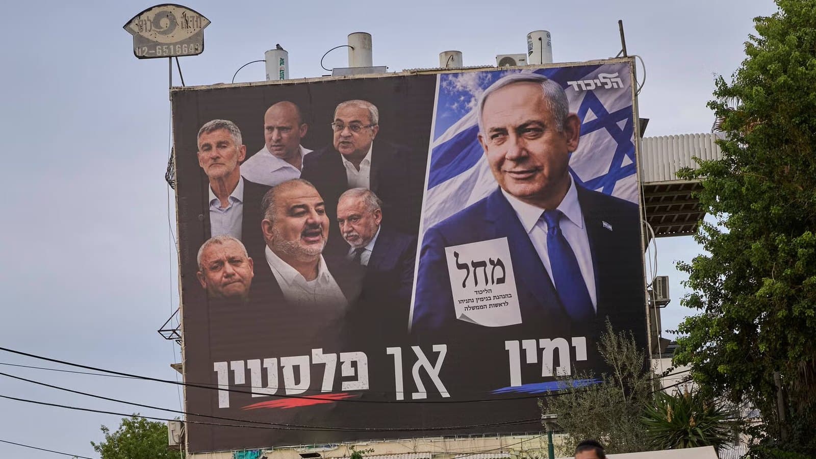 A campaign billboard in Israel showing Prime Minister Netanyahu on one side and a row of opposition leaders on the other, as pedestrians walk past.