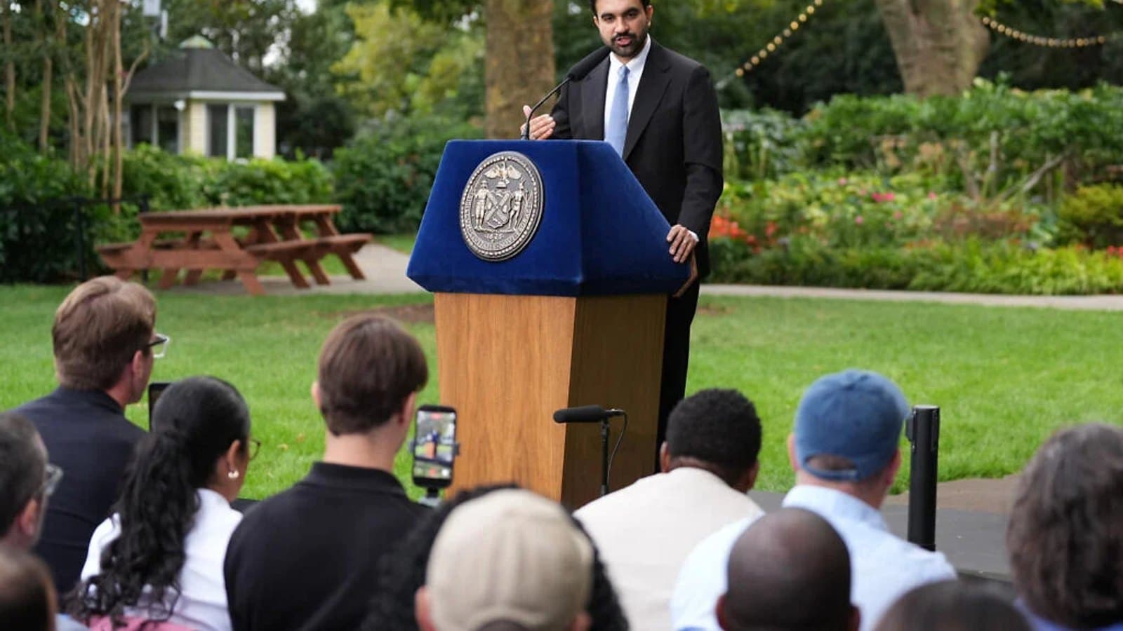New York City Mayor Zohran Mamdani speaking at a podium bearing the city seal in a park. תצלום ארכיון.