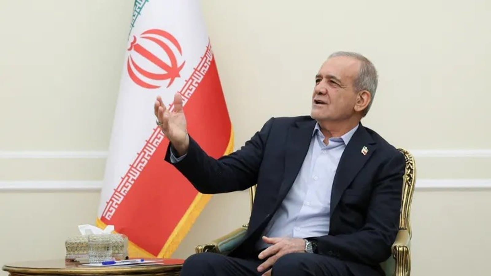Iranian President Masoud Pezeshkian speaking during a meeting, seated beside the Iranian flag. תצלום ארכיון.