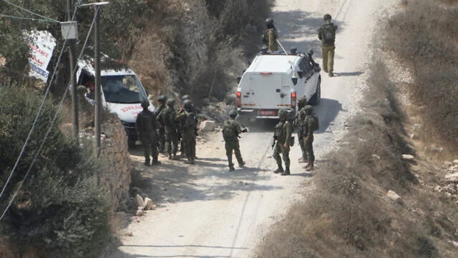 Israeli soldiers and vehicles on a road near Qusra in the West Bank.