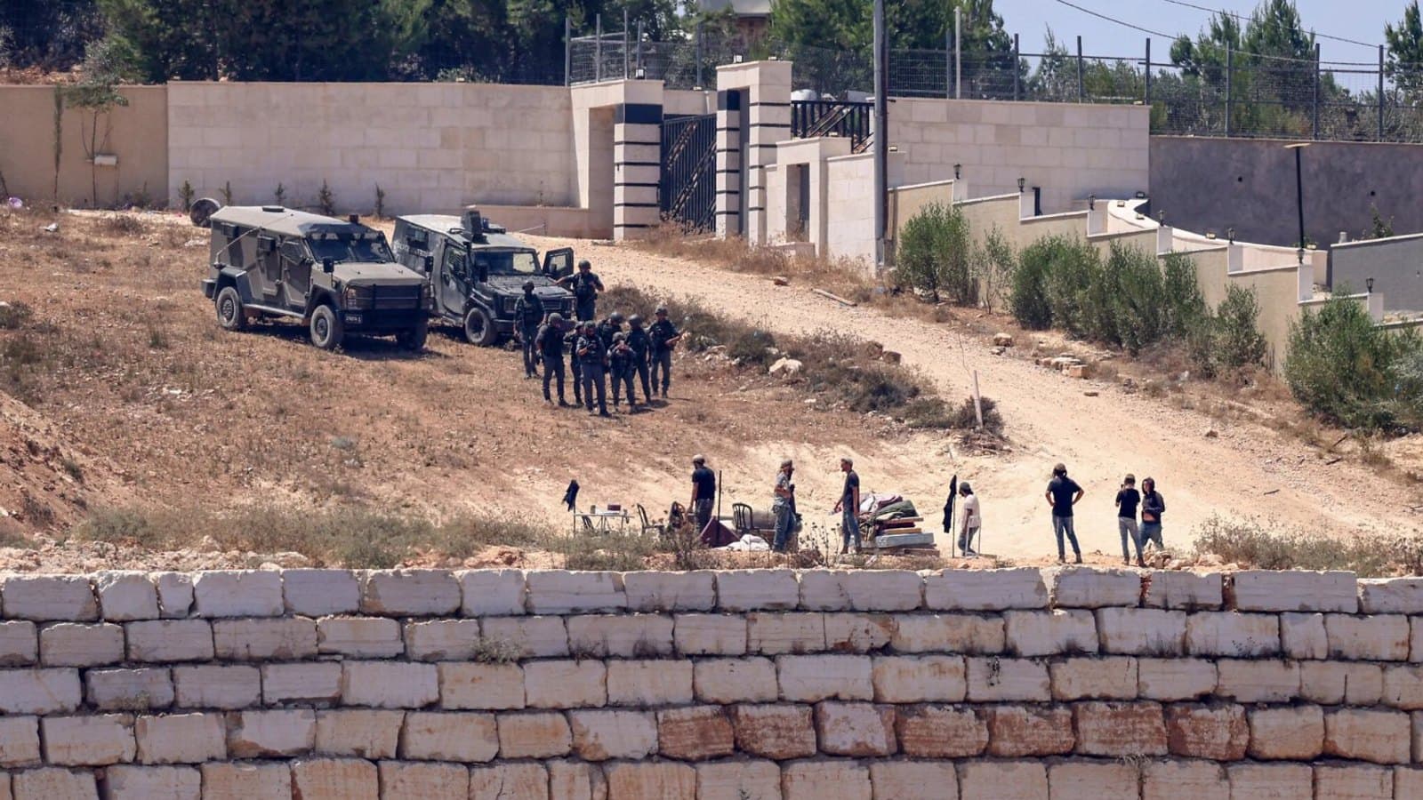 Israeli security forces and settlers on a track beside a Palestinian home near Qusra in the West Bank.