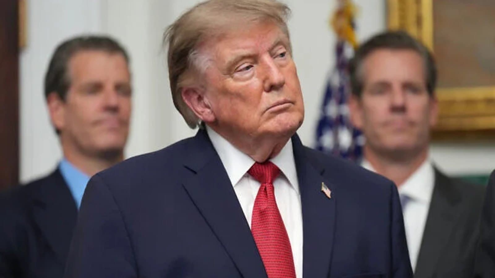 US President Donald Trump standing in a White House hallway with aides behind him. File photograph.