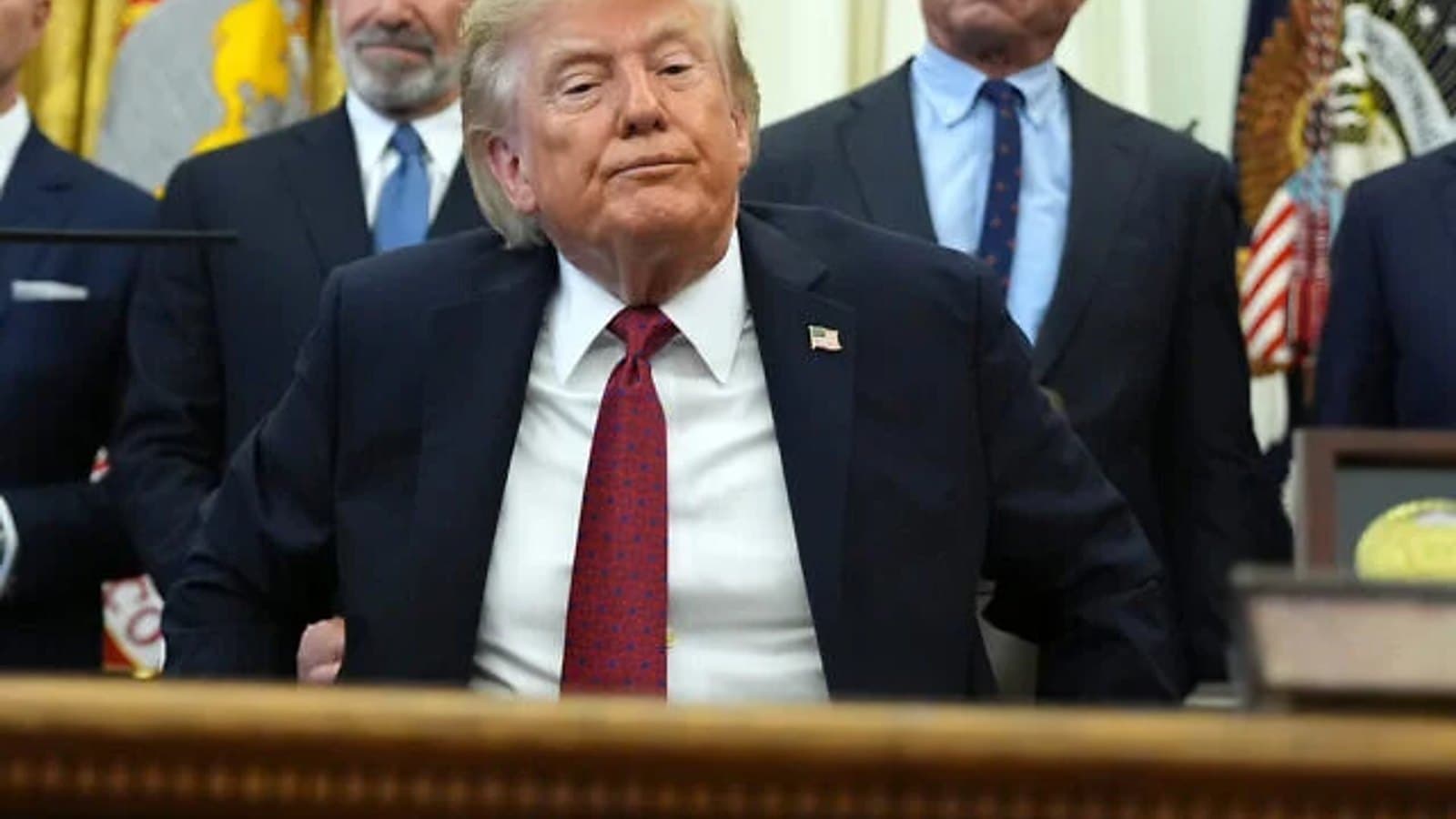US President Donald Trump standing in the Oval Office with aides behind him. File photograph.